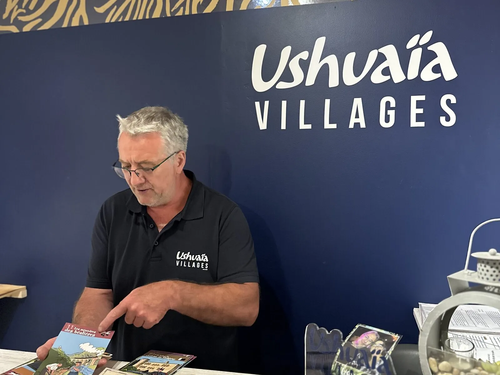 At the campsite reception, the owner shows brochures on the counter