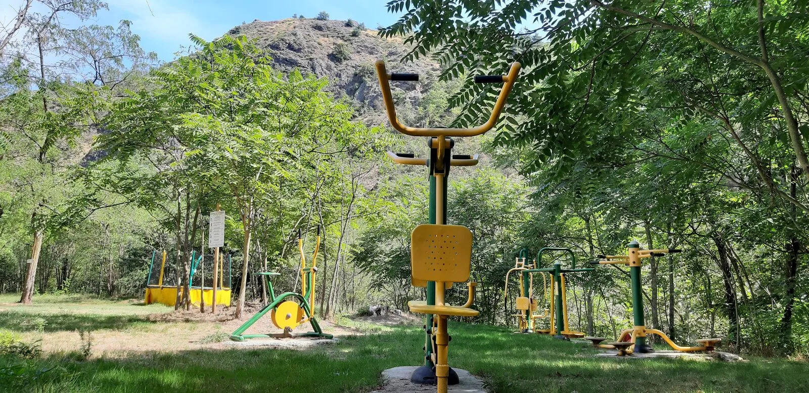 The yellow fitness equipment on the lawn, by the river