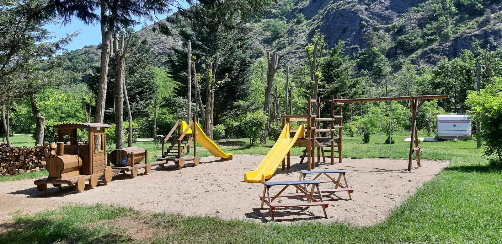 The wooden playground: the little train, the climbing frame and its yellow slides
