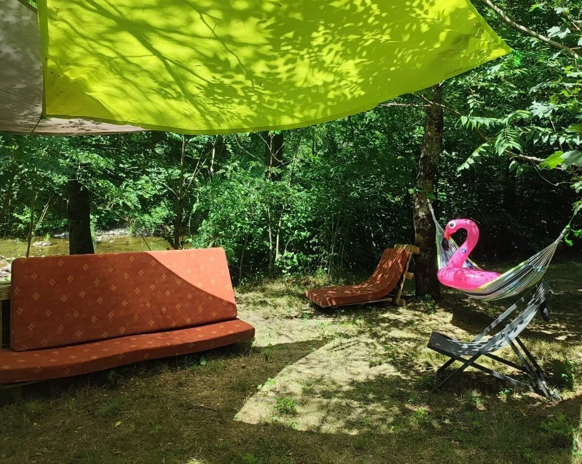 The relaxation area in the shade of a sail: bench seat, sun lounger, deckchair and hammock under the trees