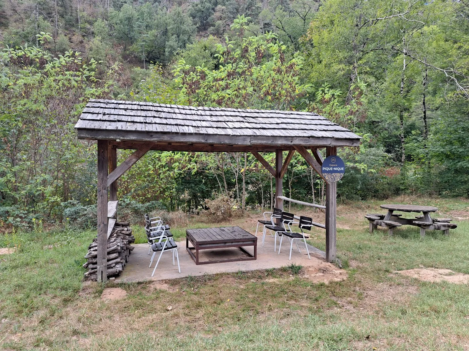 The picnic area: a wooden shelter with a low table and chairs, and a picnic table on the lawn