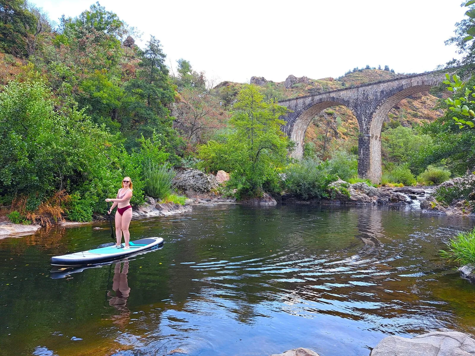 A woman paddleboarding on the Doux, in front of the viaduct