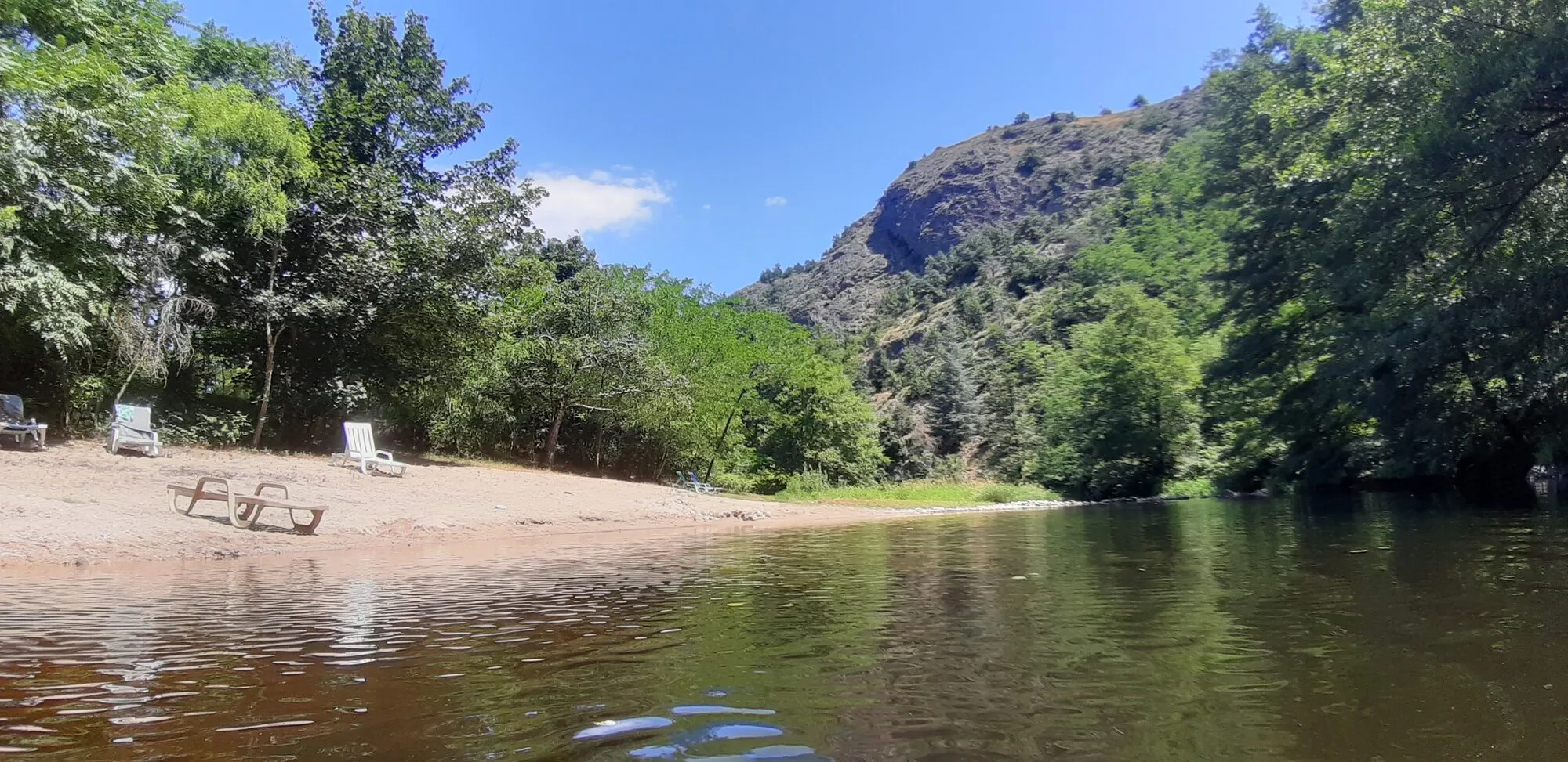 The sandy beach by the Doux, with its sun loungers and the cliff behind