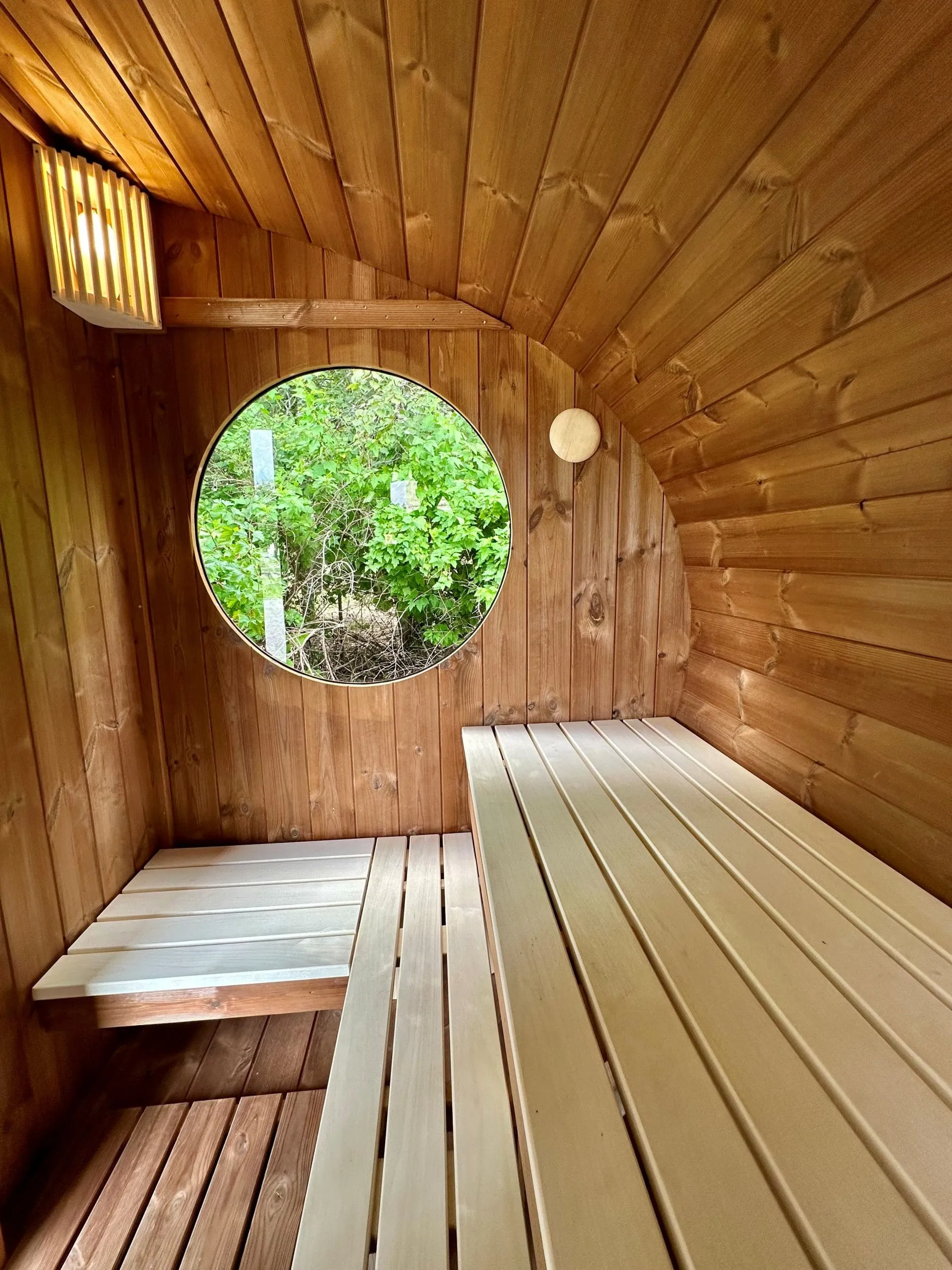 Le sauna et son hublot ouvert sur la verdure