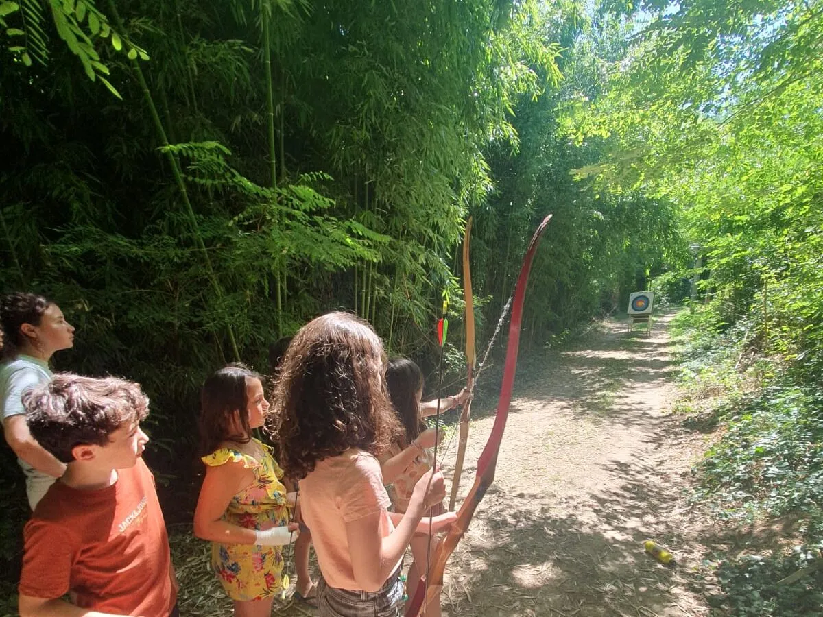 Children trying archery on a path in the campsite