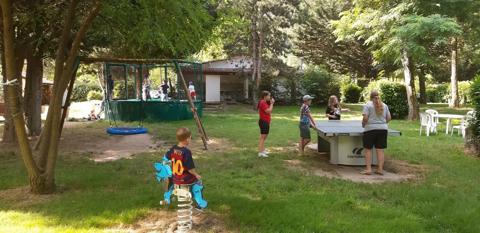 A game of table tennis in the shade of the trees, near the children's play area